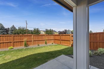 A view from a house looking out to a wooden fence and green lawn.