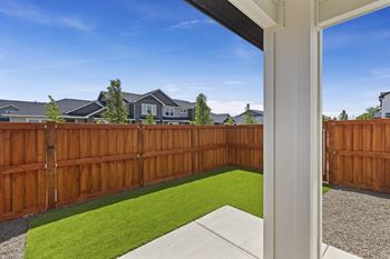 A backyard with a wooden fence and a green lawn.