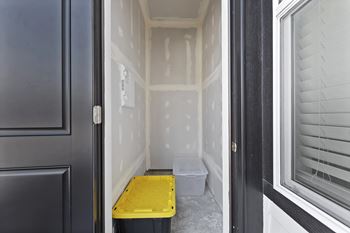 A yellow plastic bin sits on a concrete floor in a room with white walls.