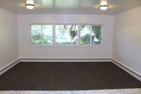 Provo apartment for rent - A room with a brown carpet and three windows.