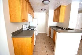 Provo apartment for rent - A kitchen with wooden cabinets and a black countertop.