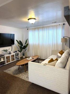 Orem apartment for rent - A living room with a white couch, a wooden coffee table, and a flat screen TV.