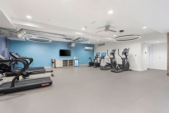 A spacious gym with treadmills, exercise bikes, and a television.