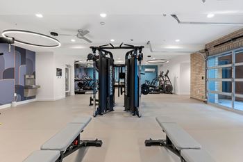 A gym with a variety of equipment including a treadmill, weights, and a bench.