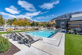 Provo apartment for rent - a swimming pool with patio furniture and a building with mountains in the background at The Flats at Riverwoods, Provo, UT