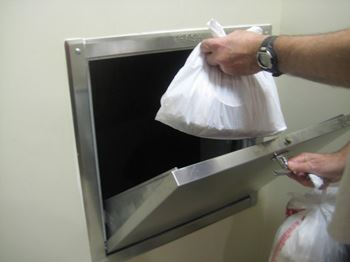 A person is cleaning a stainless steel oven with a white cloth.