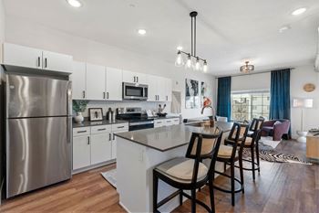 White kitchen with island seating and stainless steel appliances