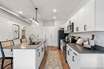 Modern kitchen with white cabinets and exposed ductwork
