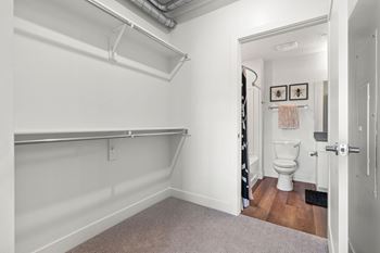 Walk-in closet with shelving and adjacent bathroom