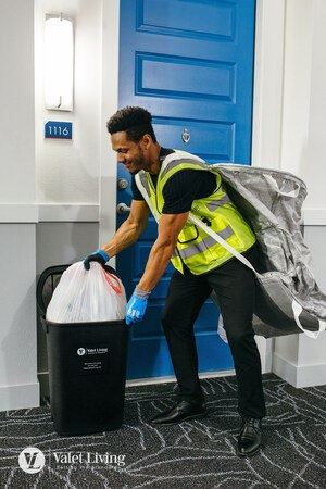Man in yellow vest and blue gloves is taking out the trash