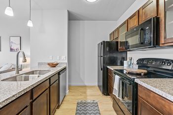 A modern kitchen with dark wood cabinets and black appliances.
