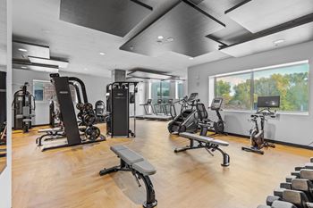 A gym with a variety of equipment including treadmills, weights, and exercise bikes.
