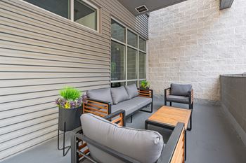 A patio with grey couches and a wooden table.