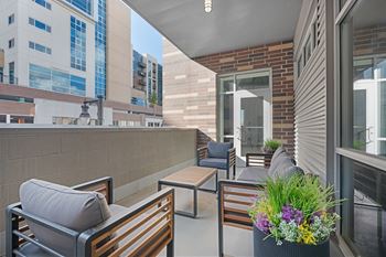 A patio with a table and chairs and a planter with flowers.