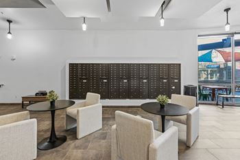 A black table is surrounded by white chairs in a room with a large black board on the wall.