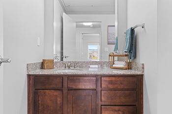 A bathroom with a brown vanity and a mirror above it.