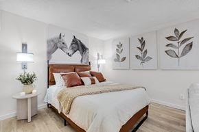 Jacksonville apartment for rent - a bedroom with a bed and paintings of horses at AVIA Lofts on Liberty Ridge Apartments, Jacksonville