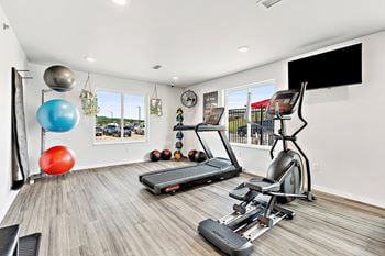 A workout room with treadmills and a flat screen tv