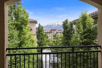 A view from a balcony looking out at a street with houses and trees.