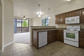 A kitchen with white appliances and brown cabinets.