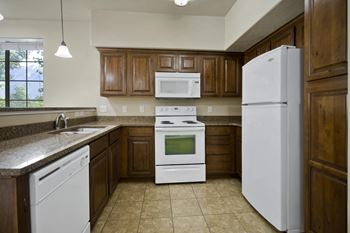 A kitchen with white appliances and brown cabinets.