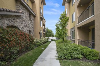 A walkway between two buildings with a stone building on the left and a tan building on the right.