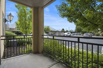 A view from a balcony looking out at a street with cars and trees.