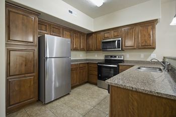A kitchen with a stainless steel refrigerator and wooden cabinets.