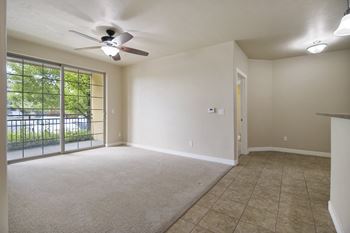 A room with a ceiling fan and sliding glass doors.