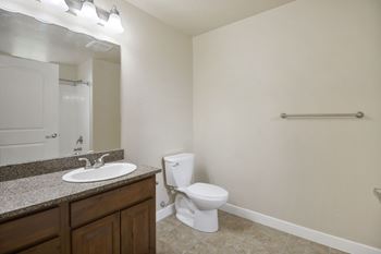 A white toilet sits in a bathroom next to a sink.