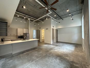 A large, empty room with a kitchen area on the left side.