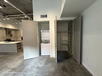 A kitchen area with a sink, stove, and refrigerator in a room with a concrete floor.