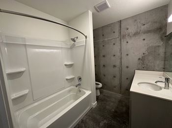A white bathtub with a shower head and a white sink with a silver faucet.