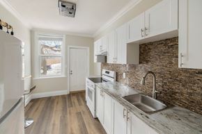 Kingston apartment for rent - A kitchen with white cabinets and a stone backsplash.