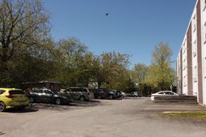 Kingston apartment for rent - A parking lot with cars and a building in the background.
