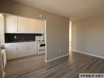 Kingston apartment for rent - A kitchen with white cabinets and a black tile backsplash.