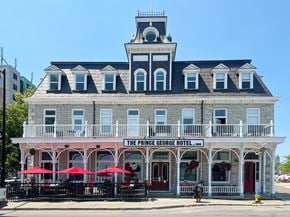 Kingston apartment for rent - The Prince George Hotel is a historic building with a balcony and red umbrellas.