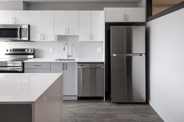 Kingston apartment for rent - a modern kitchen with stainless steel appliances and white cabinets