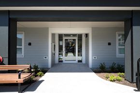 North Vancouver apartment for rent - a view of the front of the building with the doors open and a bench in front of