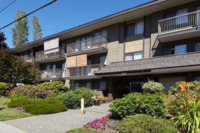 White Rock apartment for rent - a large apartment building with balconies and a garden in front of it