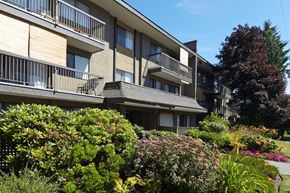 White Rock apartment for rent - a large apartment building with balconies and a garden in front of it