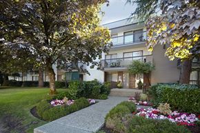 Burnaby apartment for rent - a picture of an apartment complex with a walkway in the middle of a grassy area