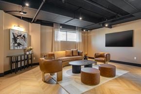 Calgary apartment for rent - A modern living room with a large couch, a coffee table, and a TV mounted on the wall.