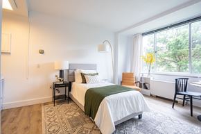 Richmond apartment for rent - A bedroom with a large bed and a chair by the window.