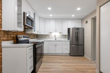 Downers Grove apartment for rent - A kitchen with white cabinets and a brick wall.