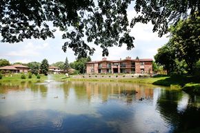 Downers Grove apartment for rent - A large house is reflected in the water of a pond.