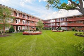 Villa Park apartment for rent - a courtyard with grass and flowers in front of an apartment building