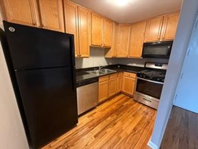 Chicago apartment for rent - A kitchen with wooden cabinets and a black refrigerator.
