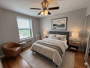 Chicago apartment for rent - A bedroom with a large bed, a chair, and a ceiling fan.