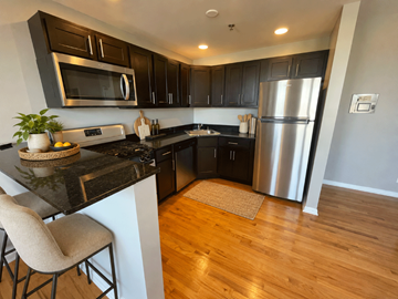 Chicago apartment for rent - A kitchen with a black counter top and a stainless steel refrigerator.